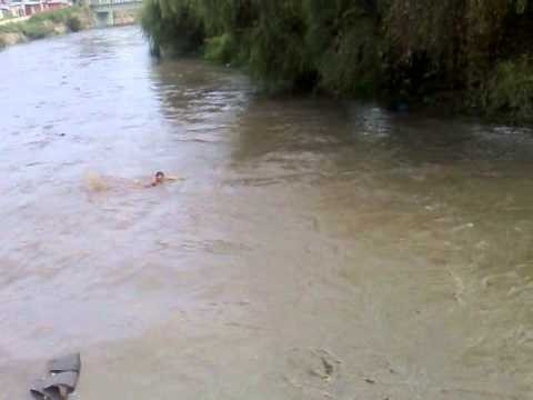 few kids diving and swimming in very dangerous flooded river